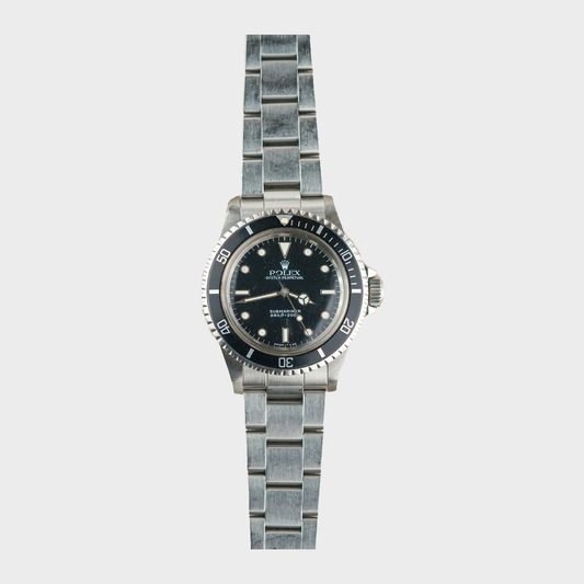 Silver watch with black dial on a light gray background