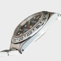 Close-up of a silver watch with a white strap on a light gray background